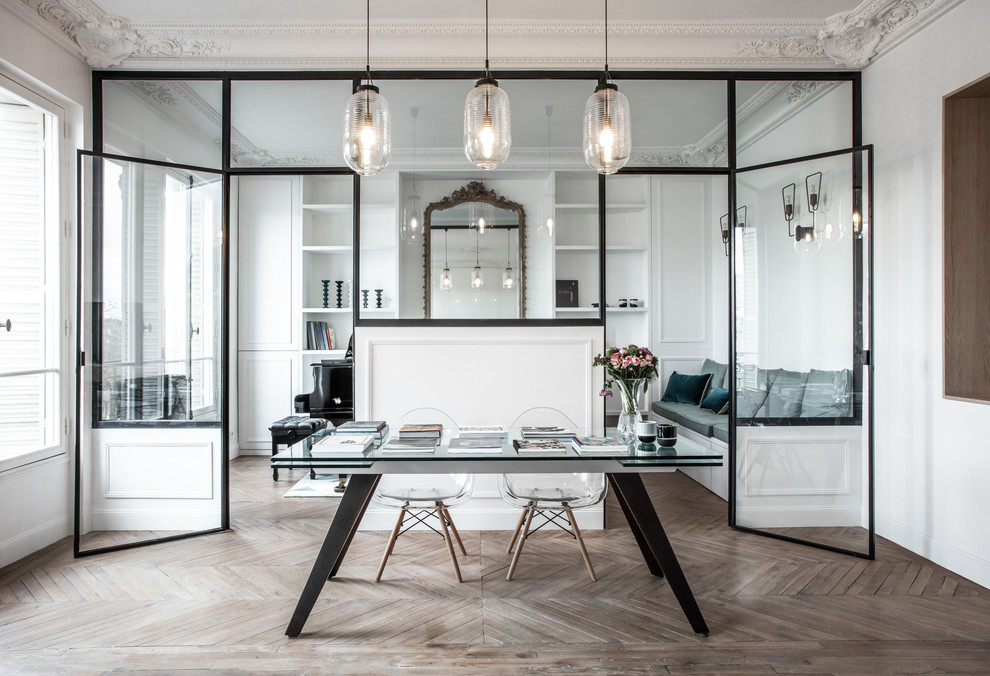 Huge trendy freestanding desk light wood floor and brown floor home office photo in Paris with white walls