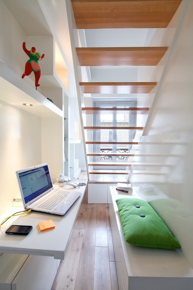 Kleines Modernes Arbeitszimmer ohne Kamin mit Arbeitsplatz, weißer Wandfarbe, hellem Holzboden, Einbau-Schreibtisch und braunem Boden in Paris