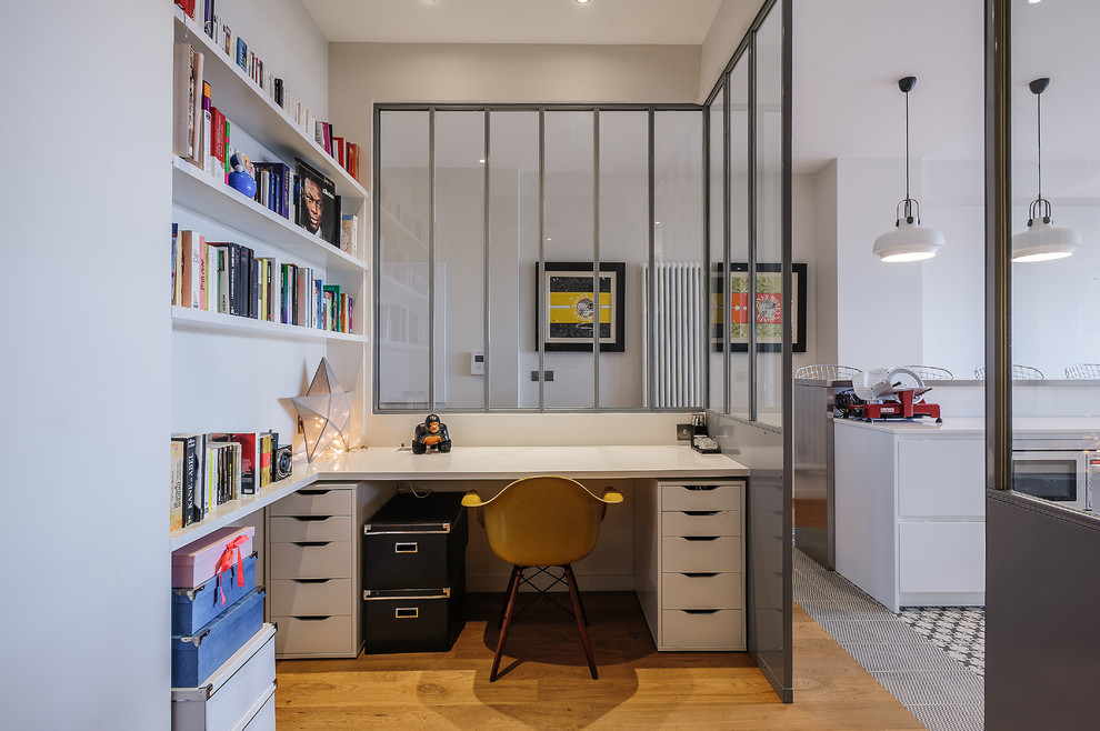 Diseño de despacho actual con paredes blancas, suelo de madera en tonos medios y escritorio empotrado