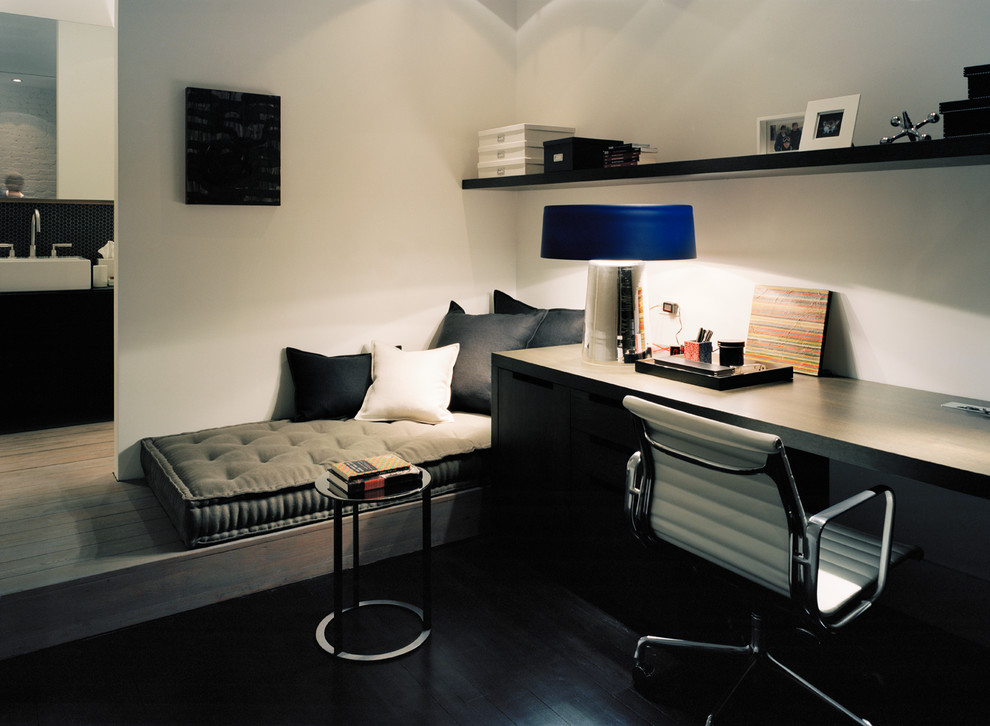 Aménagement d'un petit bureau moderne avec un mur blanc, parquet foncé et un bureau intégré.