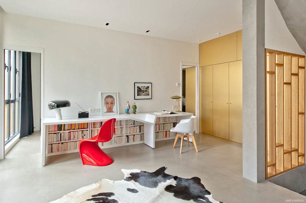 Photo of a large modern study in Paris with white walls, concrete flooring and a freestanding desk.