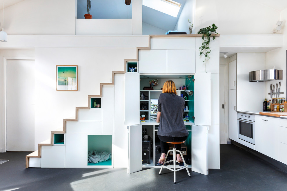 Immagine di un piccolo studio nordico con libreria, pareti bianche, pavimento in vinile, stufa a legna e pavimento grigio