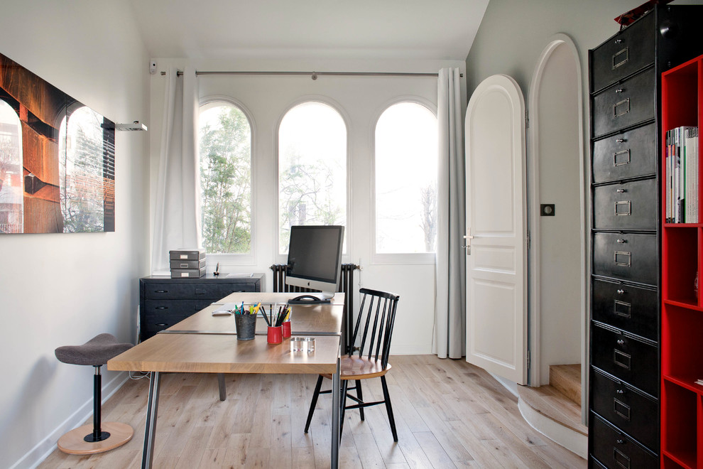 Photo of a medium sized urban study in Paris with white walls, a freestanding desk and light hardwood flooring.