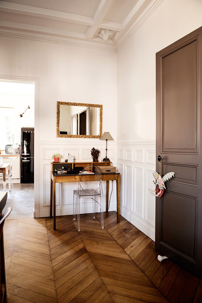 Modernes Arbeitszimmer mit Arbeitsplatz, weißer Wandfarbe, braunem Holzboden und freistehendem Schreibtisch in Paris