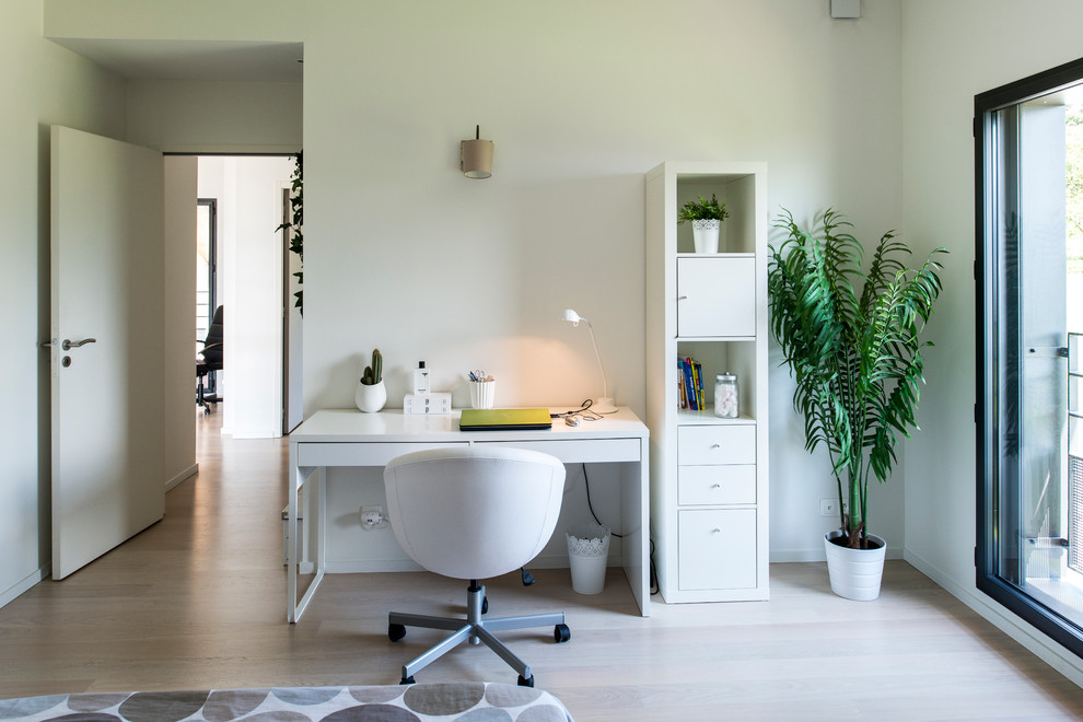 Modelo de despacho actual de tamaño medio sin chimenea con paredes blancas, suelo de madera clara y escritorio independiente