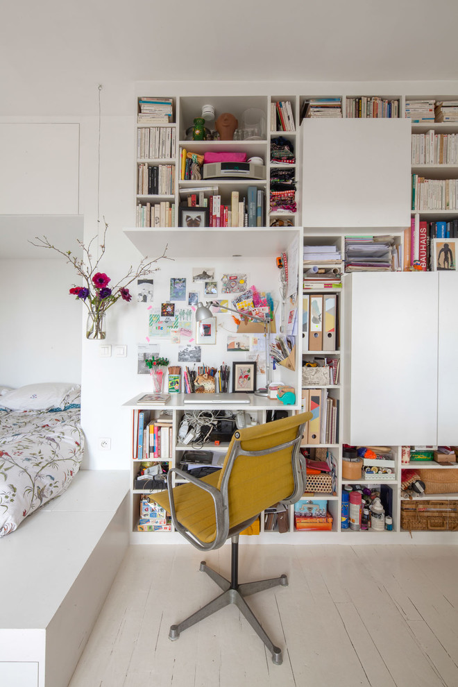 Foto på ett litet funkis arbetsrum, med vita väggar, målat trägolv, ett inbyggt skrivbord och ett bibliotek
