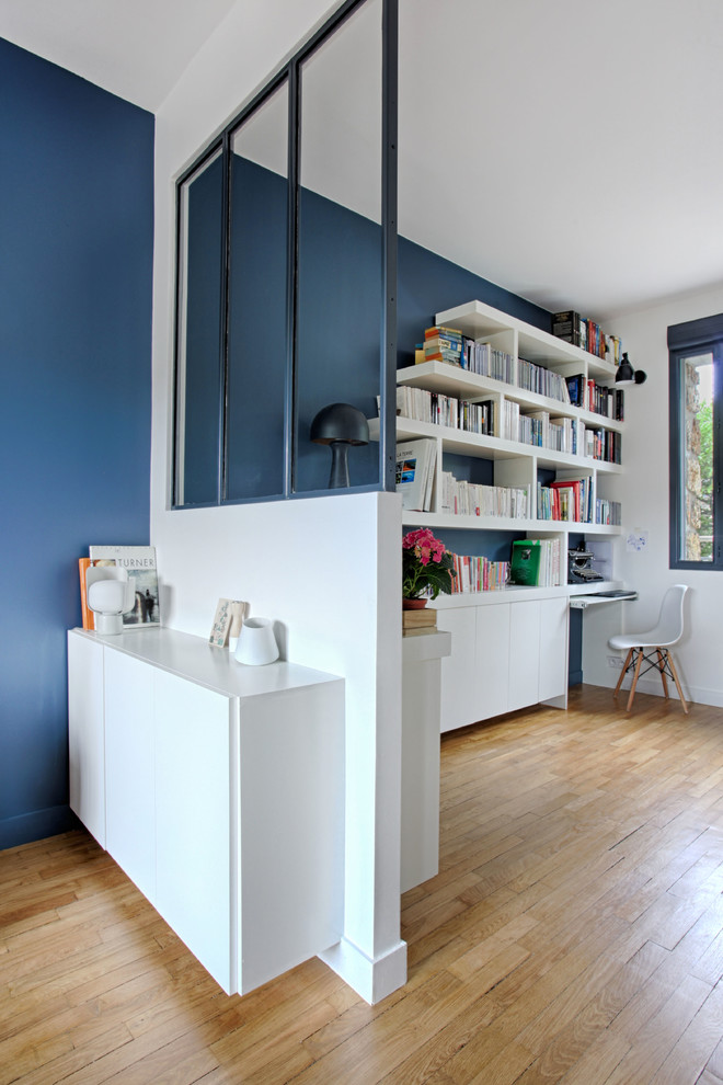 Ejemplo de despacho nórdico de tamaño medio sin chimenea con biblioteca, paredes azules, suelo de madera clara y escritorio independiente