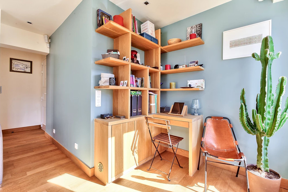 パリにある高級な中くらいなコンテンポラリースタイルのおしゃれな書斎 (青い壁、無垢フローリング、暖炉なし、造り付け机、茶色い床) の写真