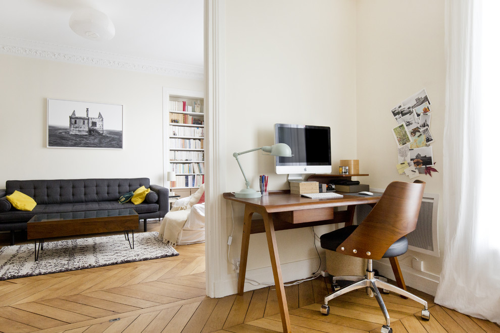 На фото: рабочее место среднего размера в современном стиле с белыми стенами, паркетным полом среднего тона и отдельно стоящим рабочим столом без камина