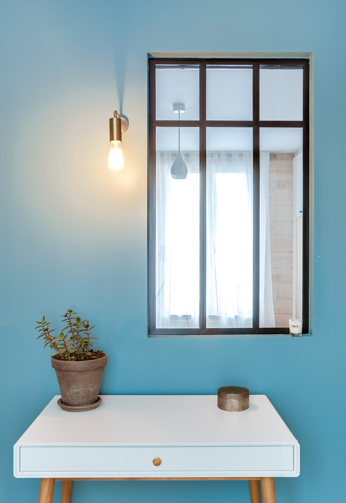 Imagen de despacho escandinavo pequeño sin chimenea con paredes azules, suelo de madera clara y escritorio independiente
