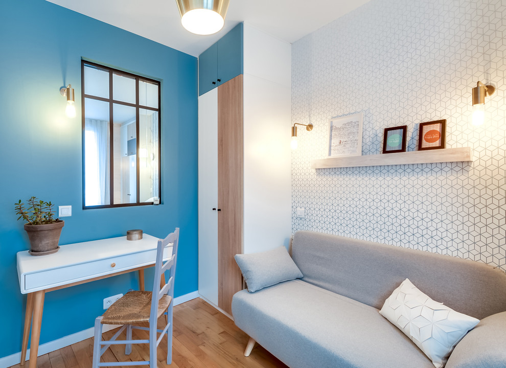 Пример оригинального дизайна: маленькое рабочее место в скандинавском стиле с синими стенами, светлым паркетным полом и отдельно стоящим рабочим столом для на участке и в саду