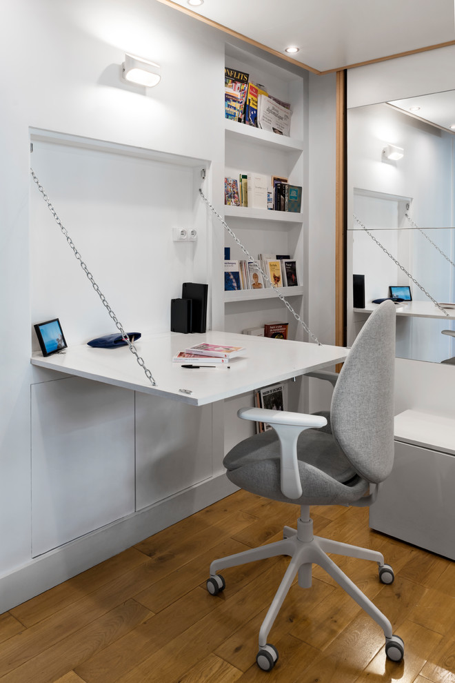 Aménagement d'un petit bureau scandinave avec un mur blanc, un sol en bois brun, aucune cheminée et un bureau intégré.