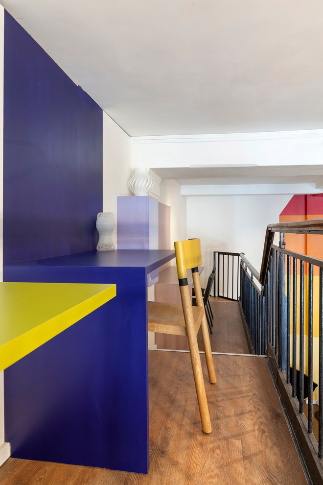 Geräumiges Modernes Arbeitszimmer mit Arbeitsplatz, blauer Wandfarbe, dunklem Holzboden und Einbau-Schreibtisch in Paris