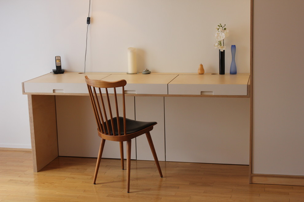 Imagen de estudio escandinavo pequeño con paredes blancas, suelo de madera clara y escritorio empotrado