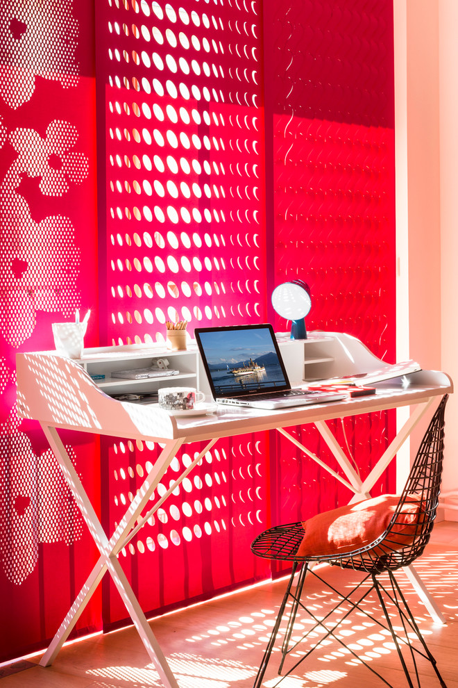 Foto på ett funkis hemmabibliotek, med ljust trägolv, ett fristående skrivbord och röda väggar