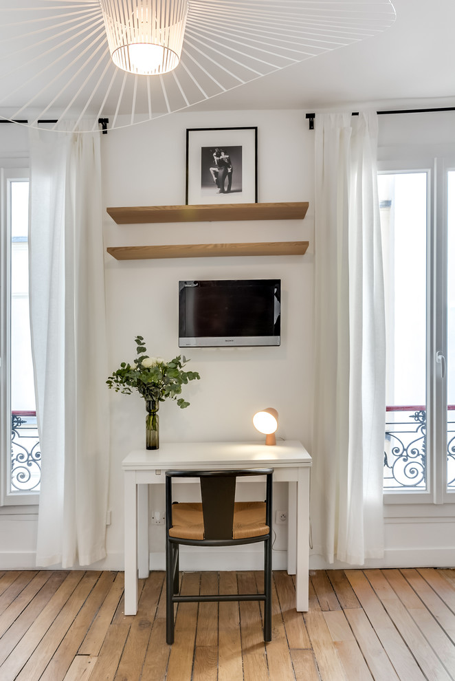Diseño de despacho contemporáneo pequeño con paredes blancas, suelo de madera clara y escritorio independiente