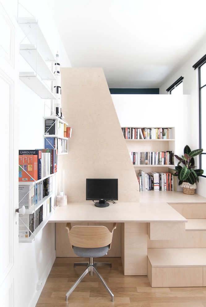 Ejemplo de despacho escandinavo pequeño sin chimenea con biblioteca, paredes blancas, suelo de madera clara y escritorio empotrado