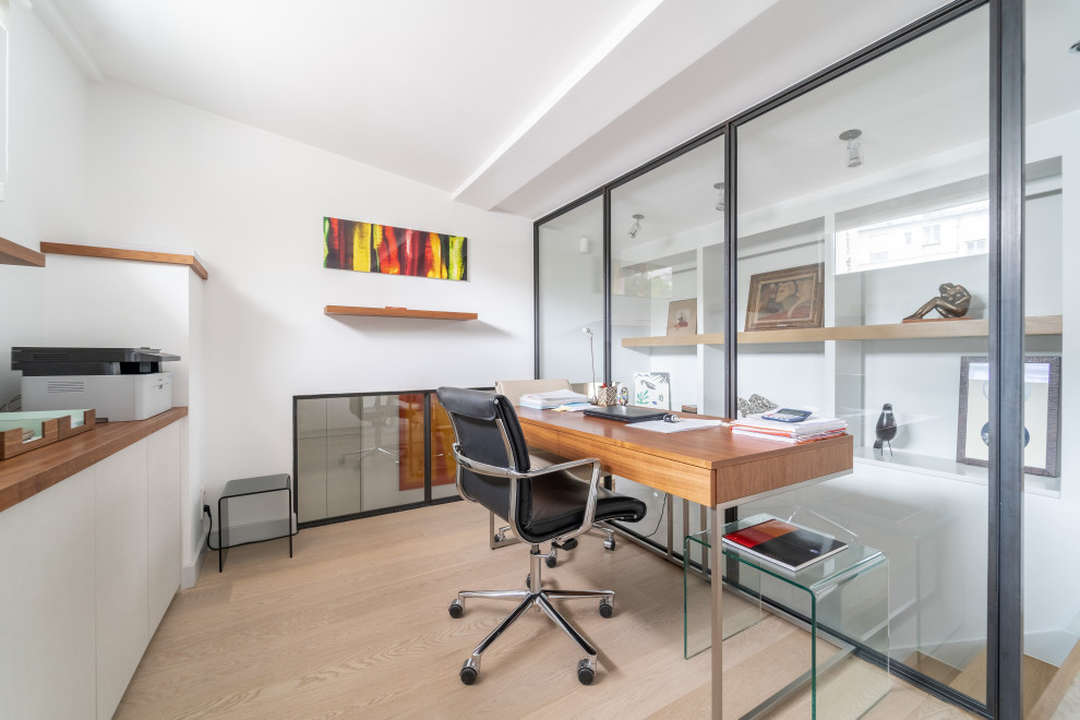Inredning av ett modernt mellanstort arbetsrum, med vita väggar, ljust trägolv, ett fristående skrivbord och beiget golv