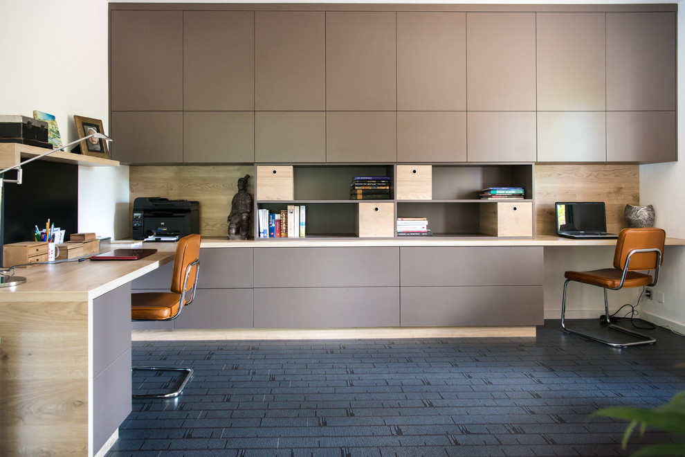 Ejemplo de despacho actual de tamaño medio con paredes blancas, suelo laminado, escritorio empotrado y suelo gris
