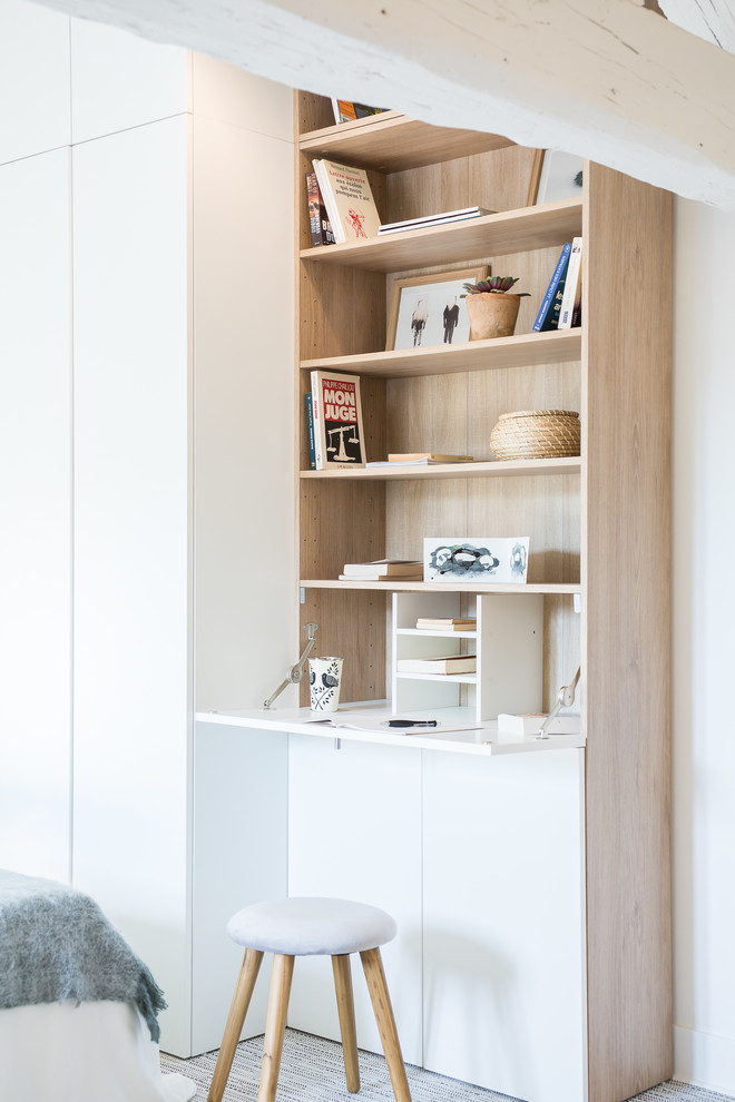 Skandinavisches Arbeitszimmer mit weißer Wandfarbe, Teppichboden, Einbau-Schreibtisch und grauem Boden in Paris