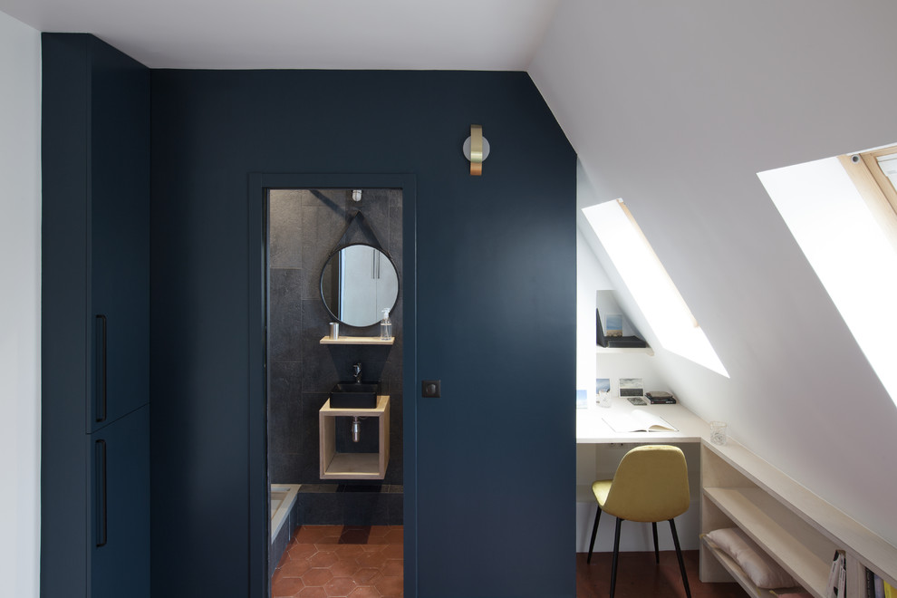 Modelo de despacho contemporáneo pequeño con paredes azules, suelo de baldosas de terracota, escritorio empotrado y suelo marrón