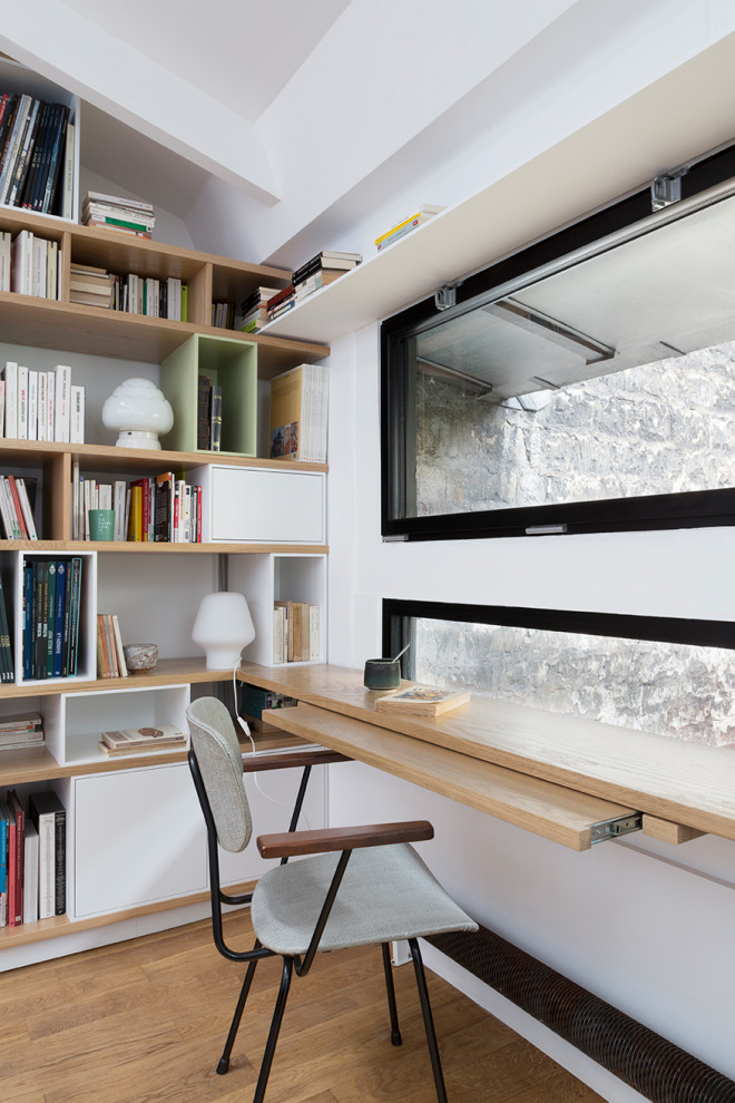 Exemple d'un grand bureau tendance avec une bibliothèque ou un coin lecture, un mur beige, un sol en bois brun, aucune cheminée, un bureau intégré et un sol beige.