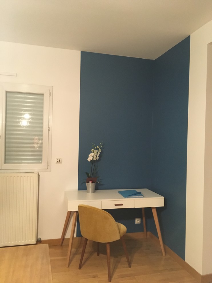 Aménagement d'un bureau contemporain de taille moyenne avec un mur bleu, parquet clair, un poêle à bois, un manteau de cheminée en métal et un sol beige.
