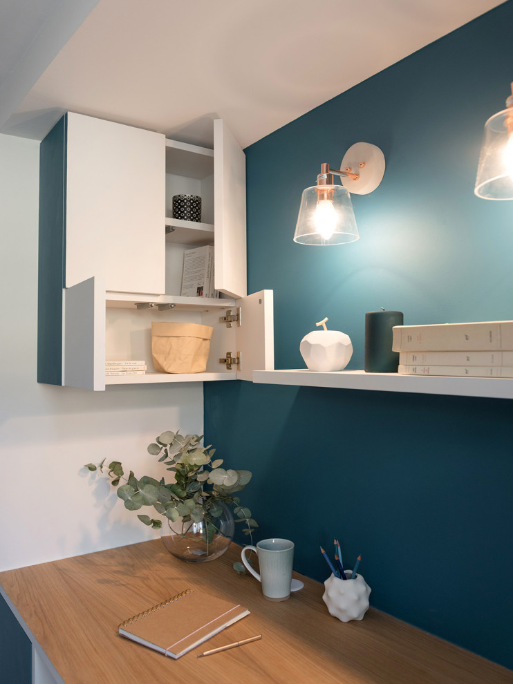 Foto de despacho actual pequeño con paredes azules, suelo de madera clara, escritorio independiente y suelo beige