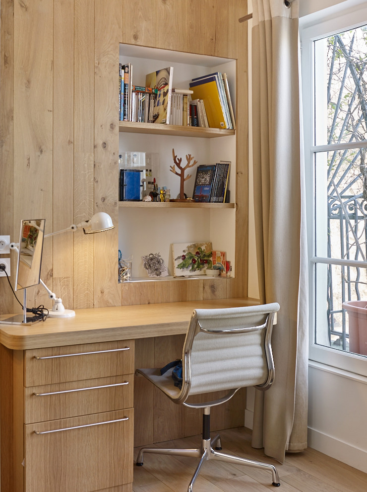 Inredning av ett skandinaviskt mellanstort hemmabibliotek, med vita väggar, ljust trägolv och ett inbyggt skrivbord