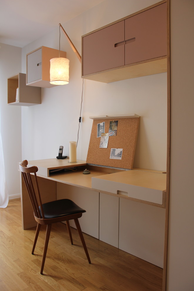 На фото: маленькая домашняя мастерская в скандинавском стиле с белыми стенами, светлым паркетным полом и встроенным рабочим столом для на участке и в саду