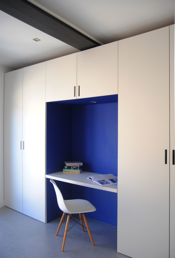 Modelo de despacho contemporáneo grande con paredes azules, suelo de baldosas de cerámica, escritorio empotrado y suelo gris