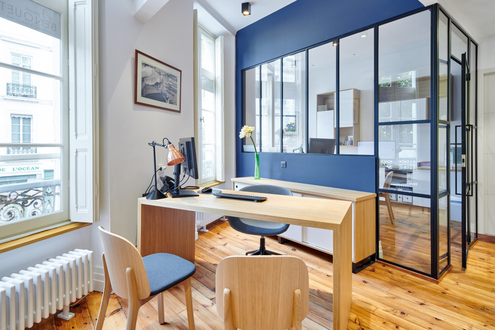 Idéer för funkis arbetsrum, med vita väggar, mellanmörkt trägolv, ett fristående skrivbord och brunt golv