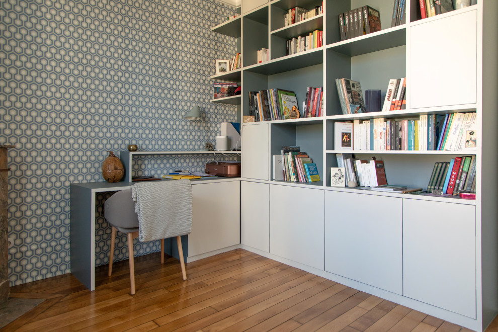 Cette photo montre un bureau moderne de taille moyenne avec un mur bleu, un sol en bois brun, une cheminée d'angle, un manteau de cheminée en pierre, un bureau intégré et un sol marron.