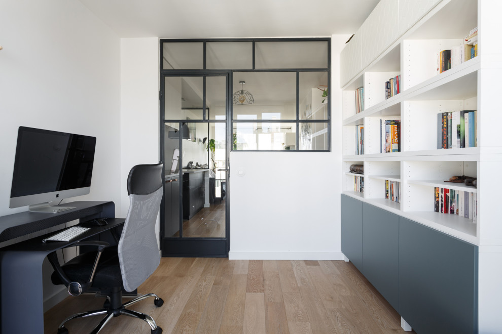 This is an example of a medium sized industrial home office in Paris with a reading nook, white walls, light hardwood flooring, no fireplace, a freestanding desk and beige floors.