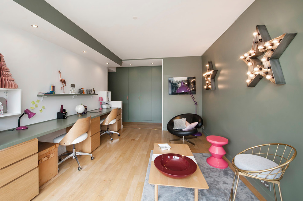 Großes Modernes Arbeitszimmer ohne Kamin mit Arbeitsplatz, grüner Wandfarbe, hellem Holzboden, freistehendem Schreibtisch und beigem Boden in Paris