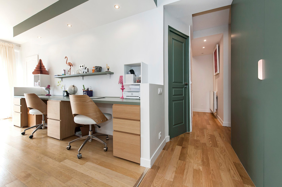 Großes Modernes Arbeitszimmer ohne Kamin mit Arbeitsplatz, grüner Wandfarbe, hellem Holzboden, freistehendem Schreibtisch und beigem Boden in Paris