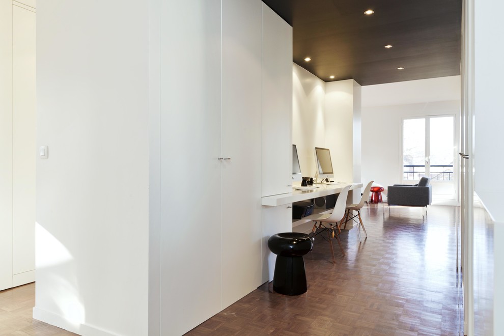 На фото: рабочее место среднего размера в современном стиле с белыми стенами, паркетным полом среднего тона и отдельно стоящим рабочим столом без камина с