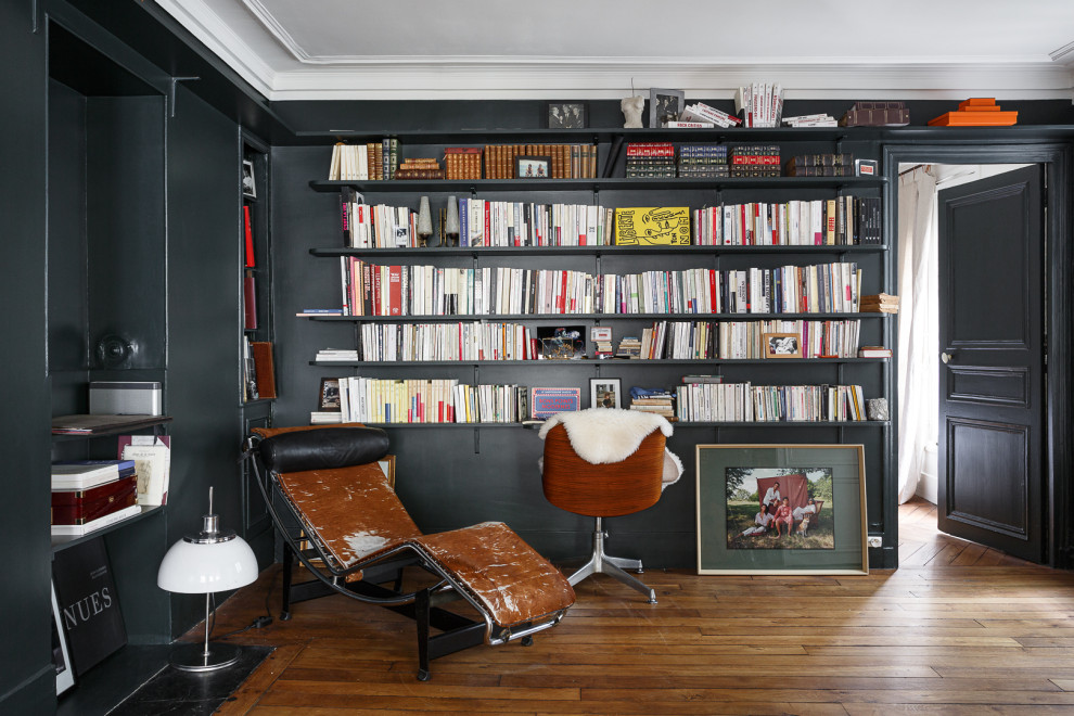 Cette image montre un bureau bohème de taille moyenne avec une bibliothèque ou un coin lecture, un mur bleu, un sol en bois brun, aucune cheminée, un bureau intégré et un sol marron.
