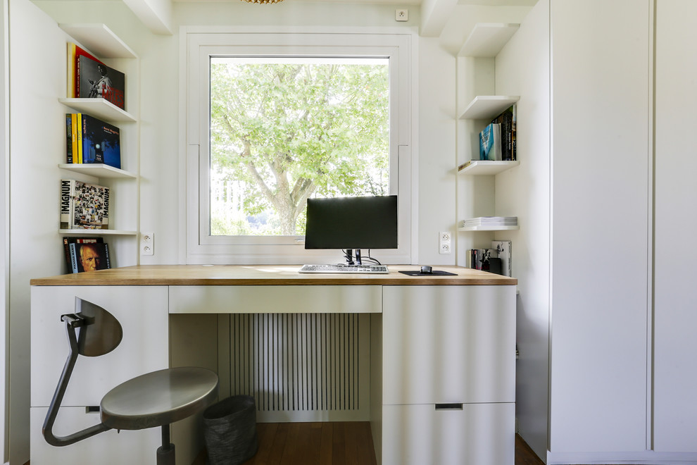 Mittelgroßes Modernes Arbeitszimmer ohne Kamin mit Arbeitsplatz, weißer Wandfarbe, hellem Holzboden, freistehendem Schreibtisch und braunem Boden in Paris