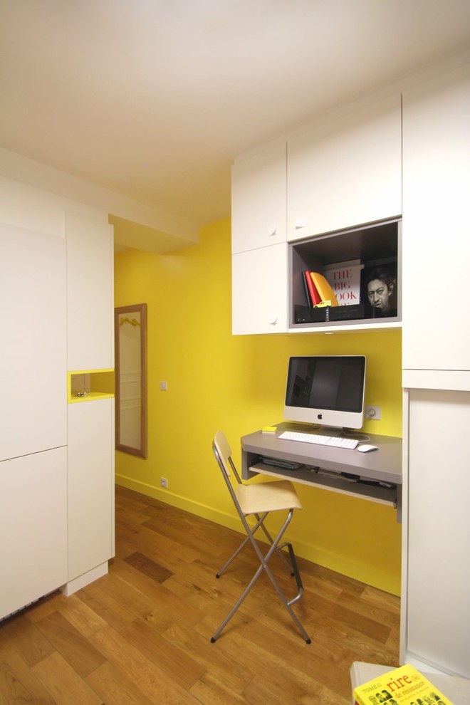 Cette image montre un petit bureau minimaliste avec un mur jaune, parquet clair, un bureau intégré et aucune cheminée.