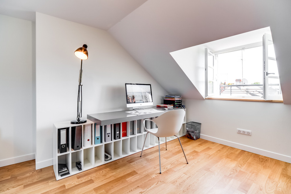Cette image montre un bureau design de taille moyenne avec un mur blanc, parquet clair, un bureau indépendant et un sol marron.