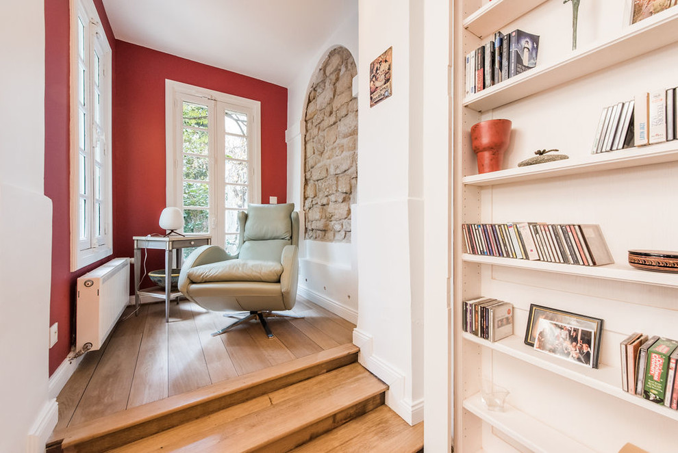 Exemple d'un bureau tendance de taille moyenne avec une bibliothèque ou un coin lecture, un mur rouge, un sol en bois brun, aucune cheminée et un sol beige.