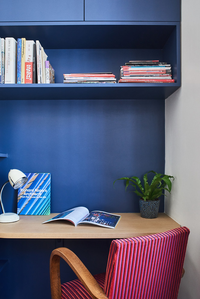 Ejemplo de despacho actual pequeño sin chimenea con paredes azules, suelo de madera en tonos medios y escritorio empotrado