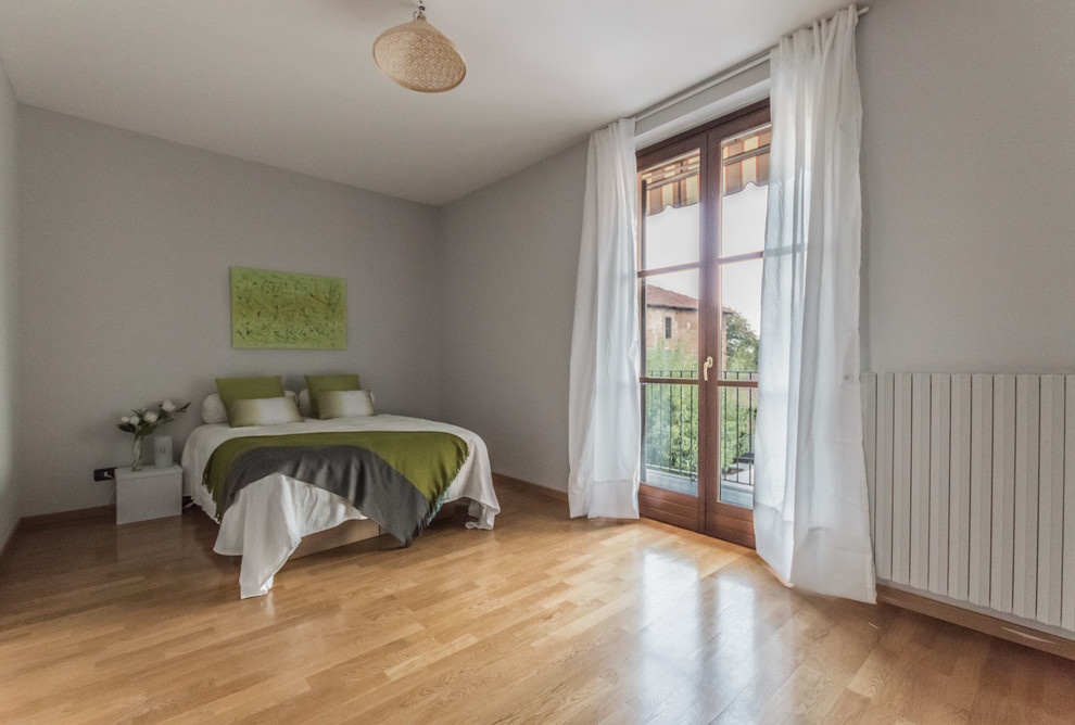 На фото: хозяйская спальня среднего размера в стиле модернизм с серыми стенами и деревянным полом без камина