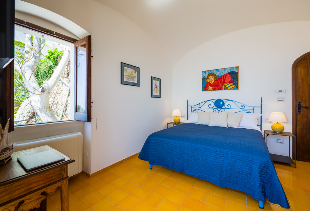 Idée de décoration pour une chambre parentale méditerranéenne de taille moyenne avec un mur blanc, un sol jaune, un plafond voûté et un sol en carrelage de céramique.