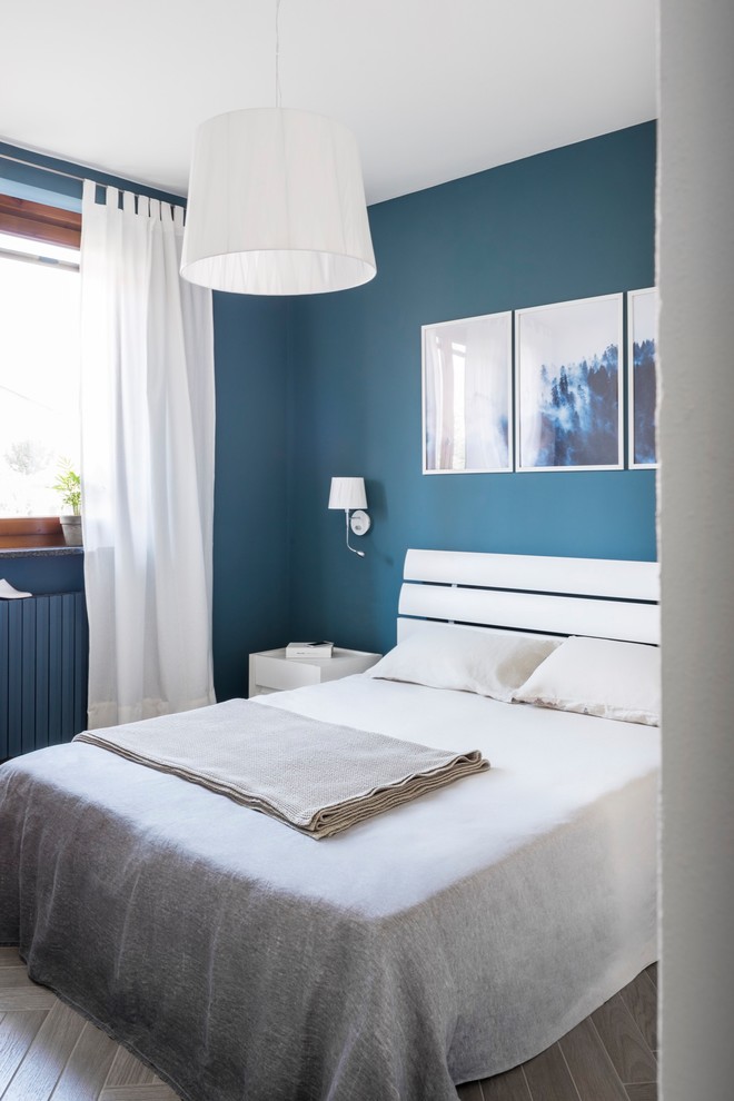 Cette image montre une petite chambre parentale design avec un mur bleu, un sol en carrelage de porcelaine et un sol marron.