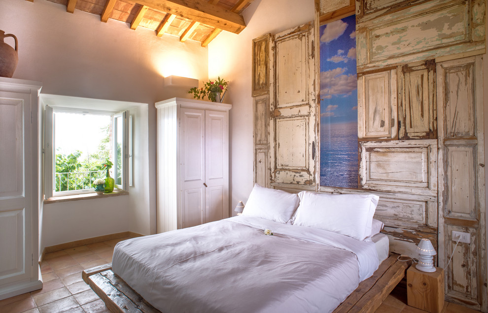 На фото: спальня в средиземноморском стиле с белыми стенами, полом из терракотовой плитки и коричневым полом