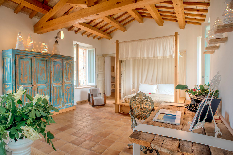Пример оригинального дизайна: спальня в средиземноморском стиле с белыми стенами, полом из терракотовой плитки и коричневым полом