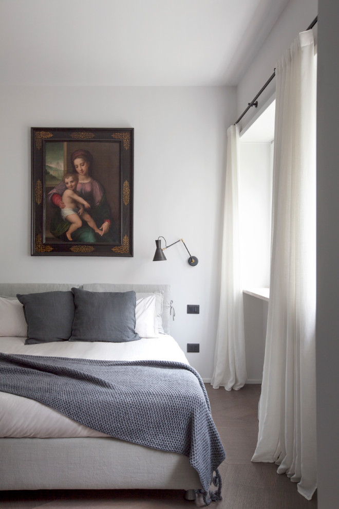 Modernes Schlafzimmer mit weißer Wandfarbe, dunklem Holzboden und braunem Boden in Mailand