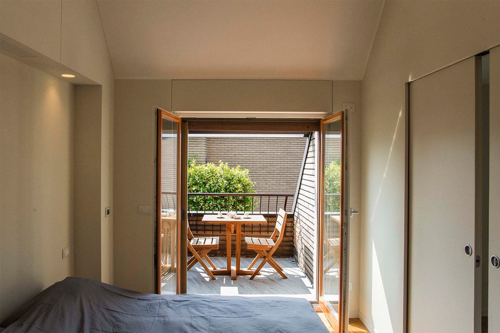 Modelo de dormitorio principal contemporáneo de tamaño medio con paredes beige y suelo de madera en tonos medios